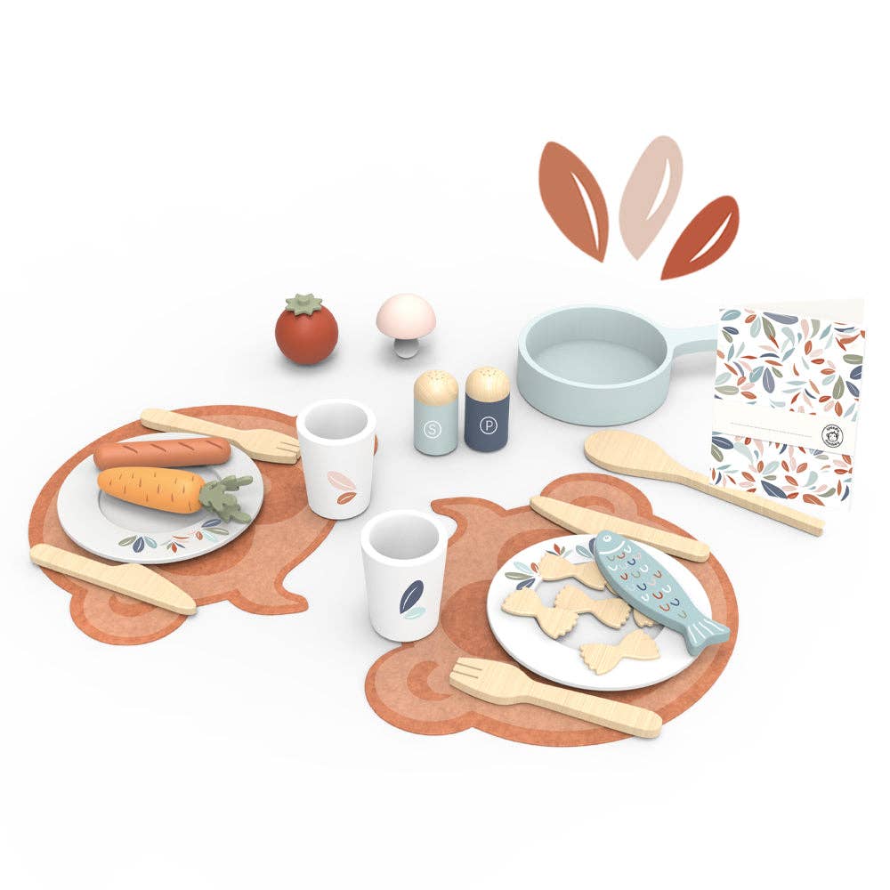 Wooden play dining set for two with plates, utensils, pasta, fish, and vegetables, arranged on bear-shaped placemats.