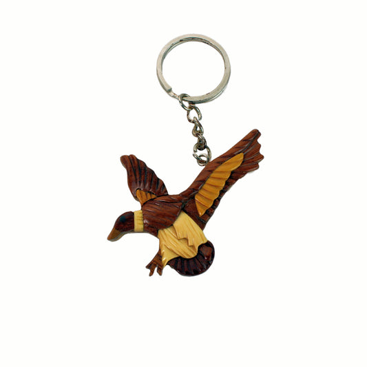 Wooden duck keychain with outstretched wings in flight position, carved from light and dark wood pieces.