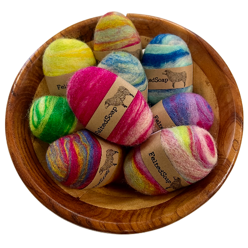 Multicolored felted soap bars in vibrant hues, each wrapped with a natural label.