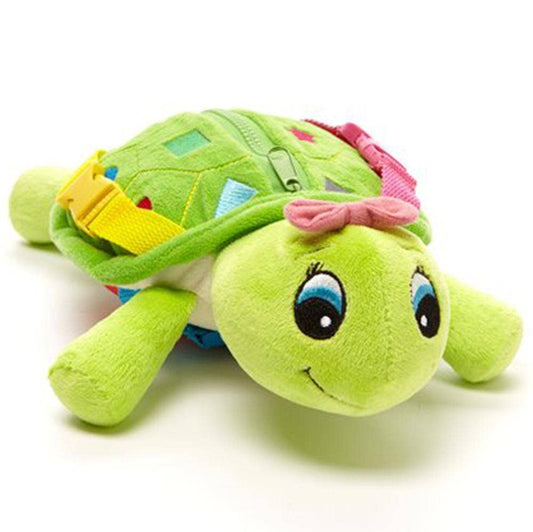 Plush green turtle toy with colorful buckles, zipper, and embroidered shapes