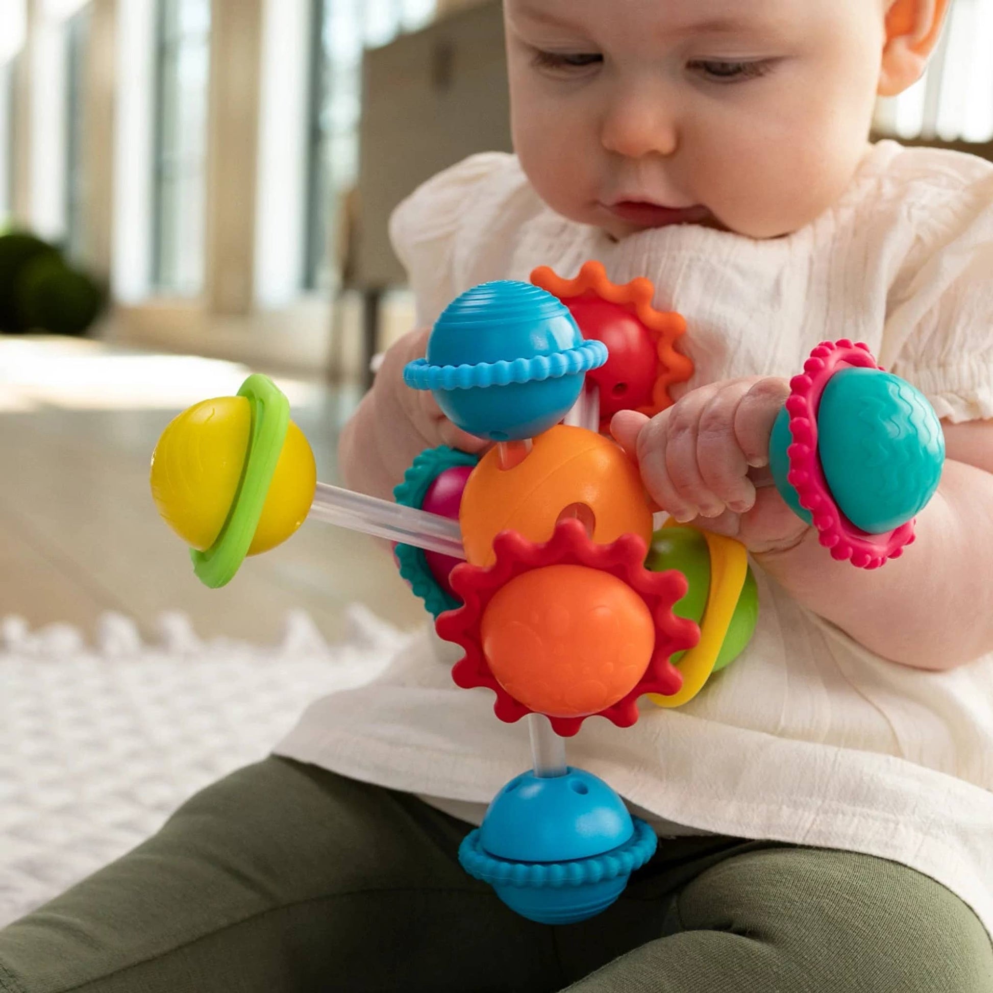 Multicolor sensory toy with spinning silicone rings and textured shapes for baby play.