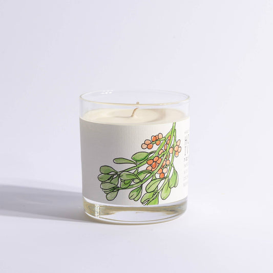 Glass holiday candle with illustrated holly and ivy label.