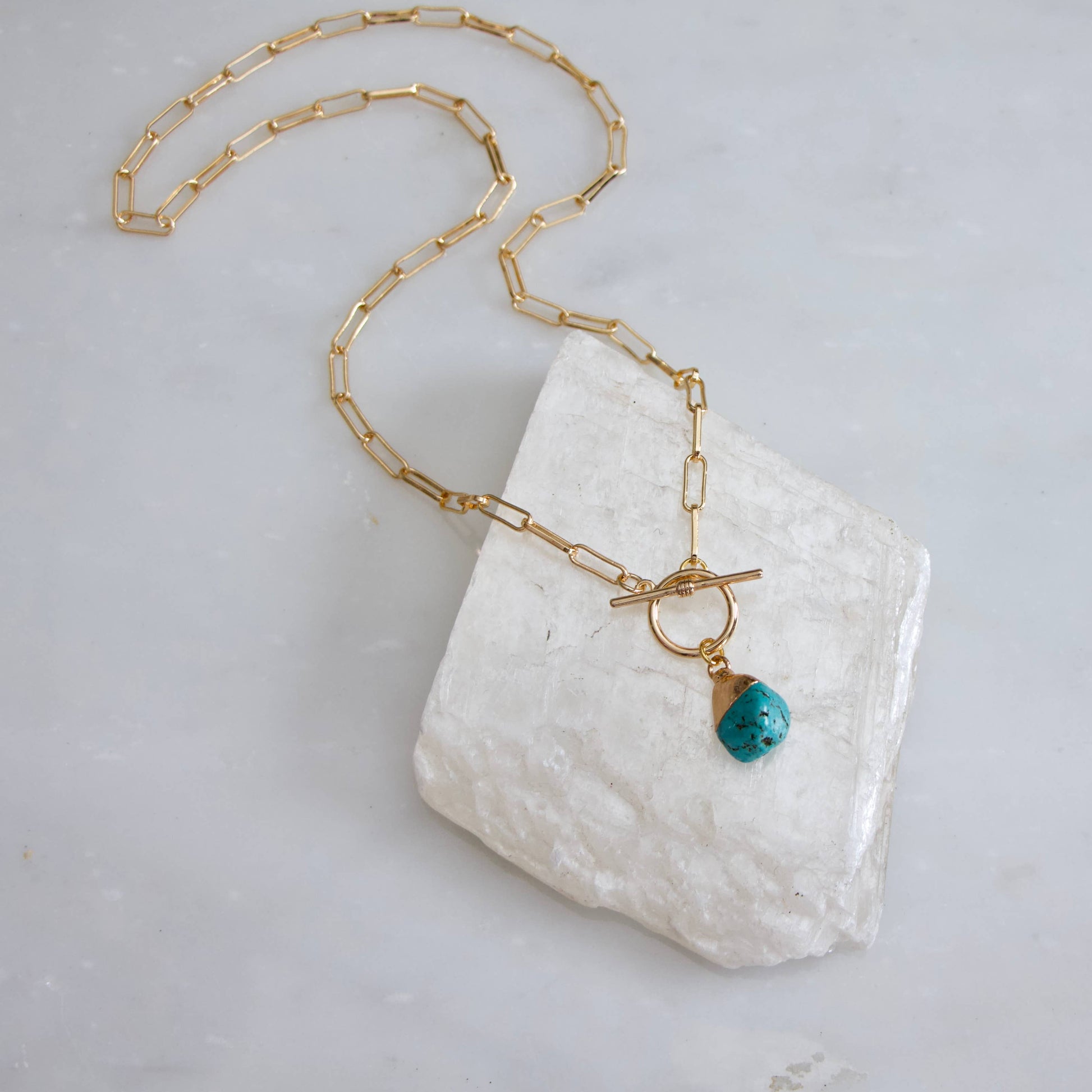 Gold paperclip chain necklace featuring a turquoise nugget pendant and a toggle clasp.