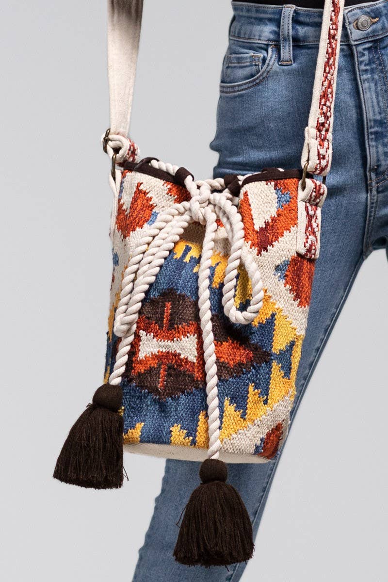 Handwoven bucket bag with geometric tribal patterns, a thick rope drawstring closure, and black tassel accents.