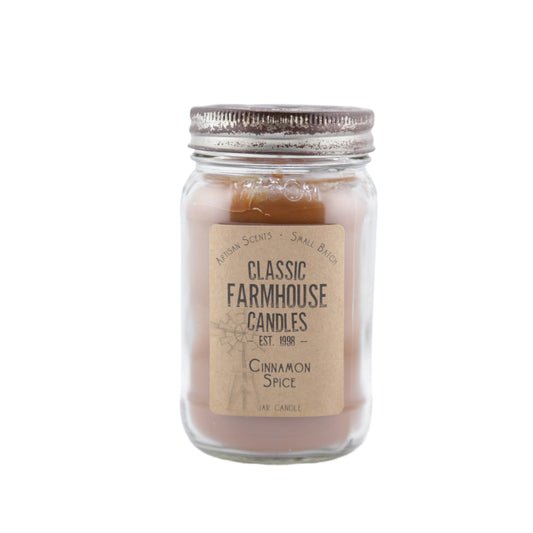 Warm brown candle in a mason jar labeled "Cinnamon Spice" with vintage-style metal lid and star cutout.
