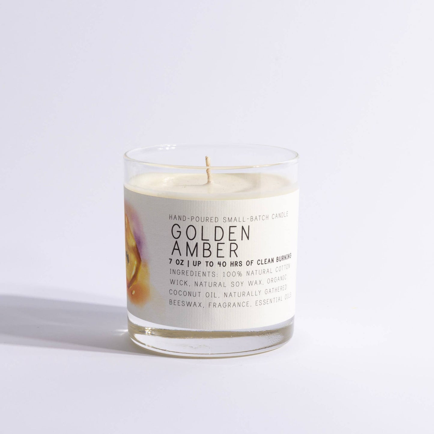 Golden amber candle in a clear glass jar with minimalist label