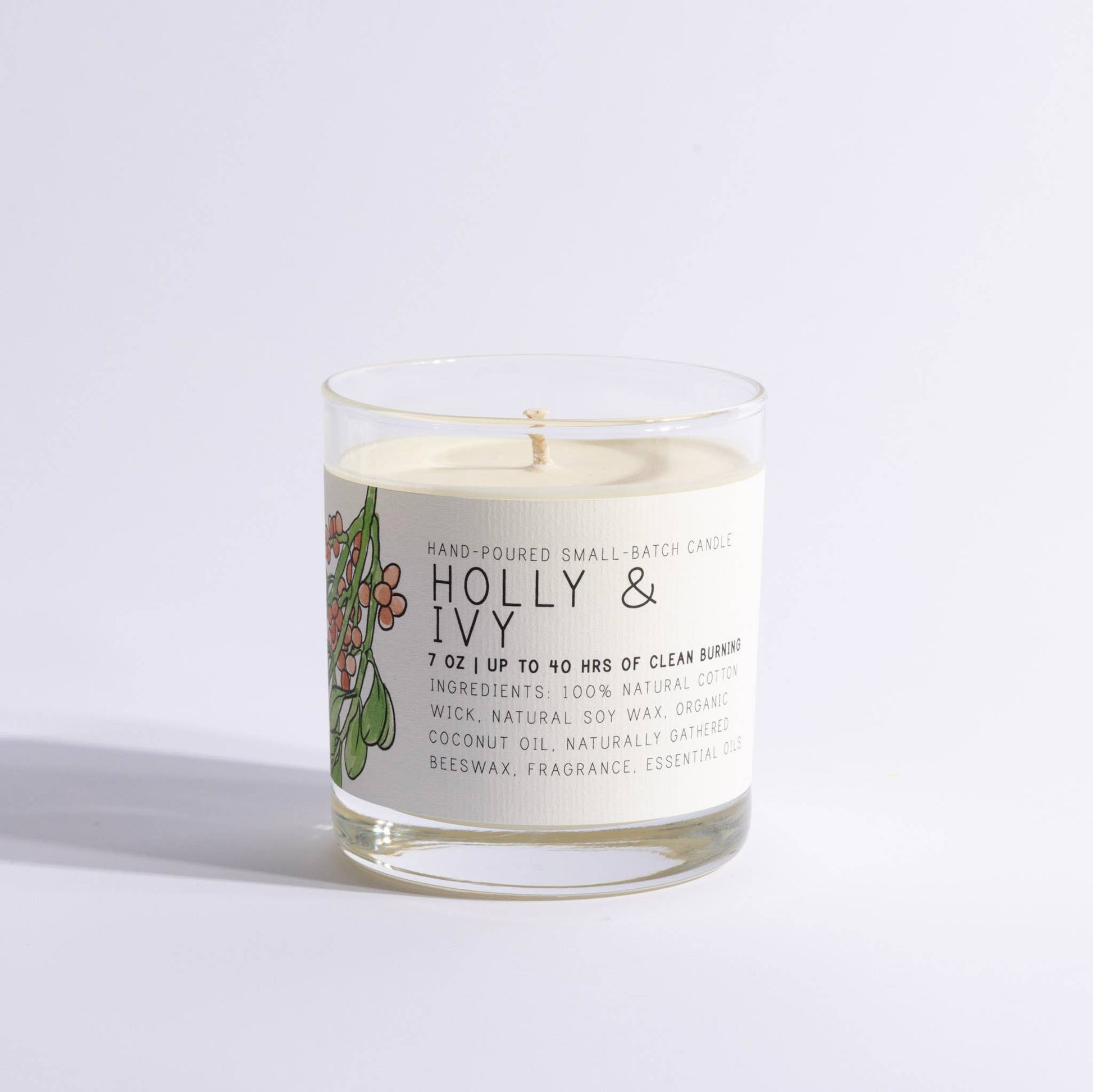 Holiday scented Holly & Ivy candle in glass jar with white label and cotton wick.
