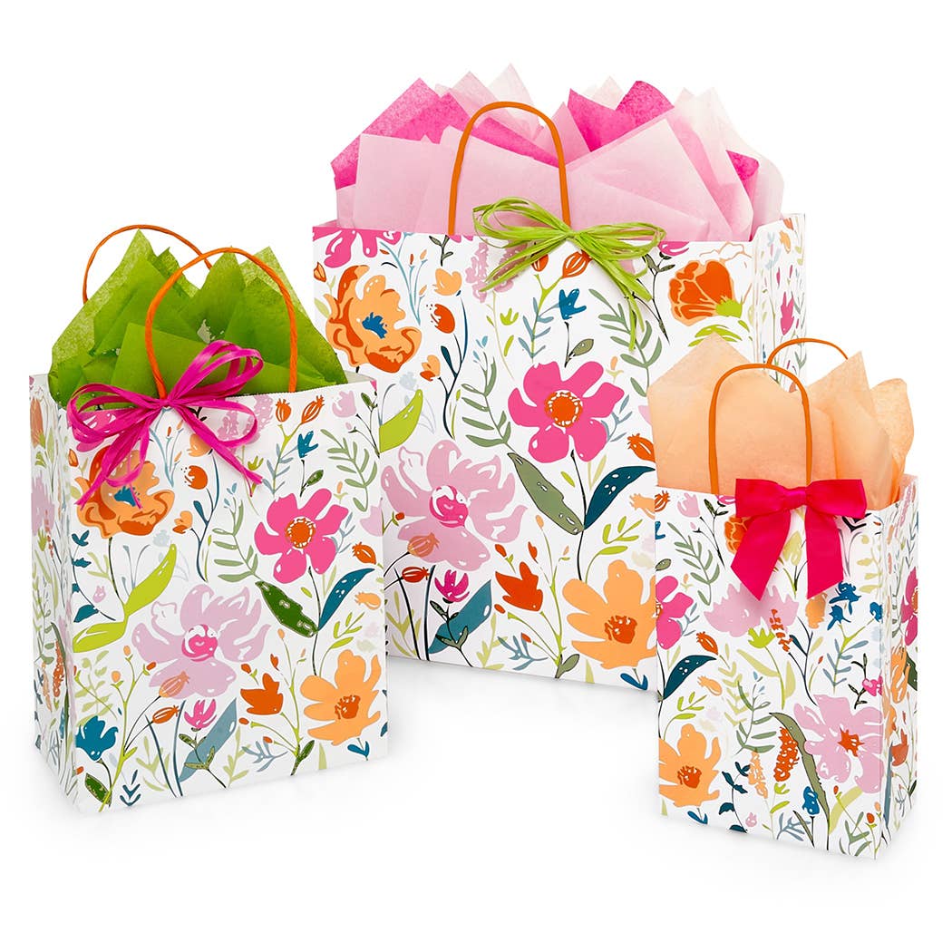 Floral gift bags in various sizes with bright pink, orange, and green wildflowers on a white background, each filled with coordinating tissue paper and colorful bows.
