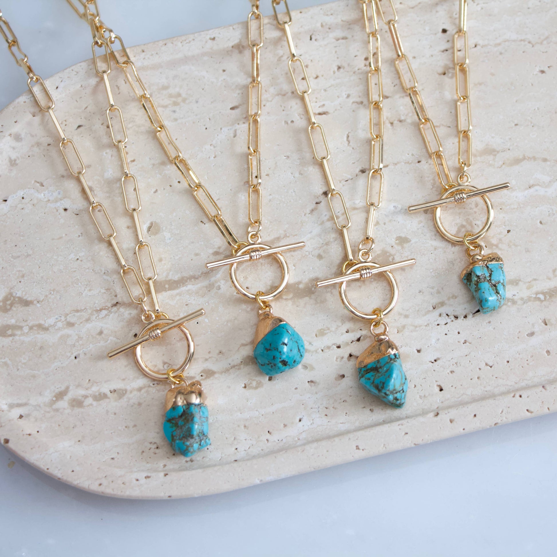 Gold paperclip chain necklace with a turquoise nugget pendant and a toggle clasp.