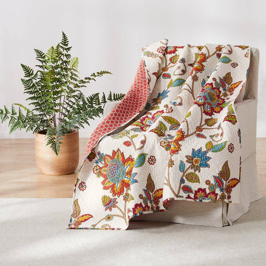 Colorful floral quilted throw draped over a neutral armchair