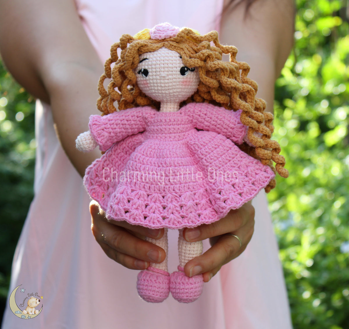 Crochet doll with curly blonde hair, wearing a pink dress and matching shoes.