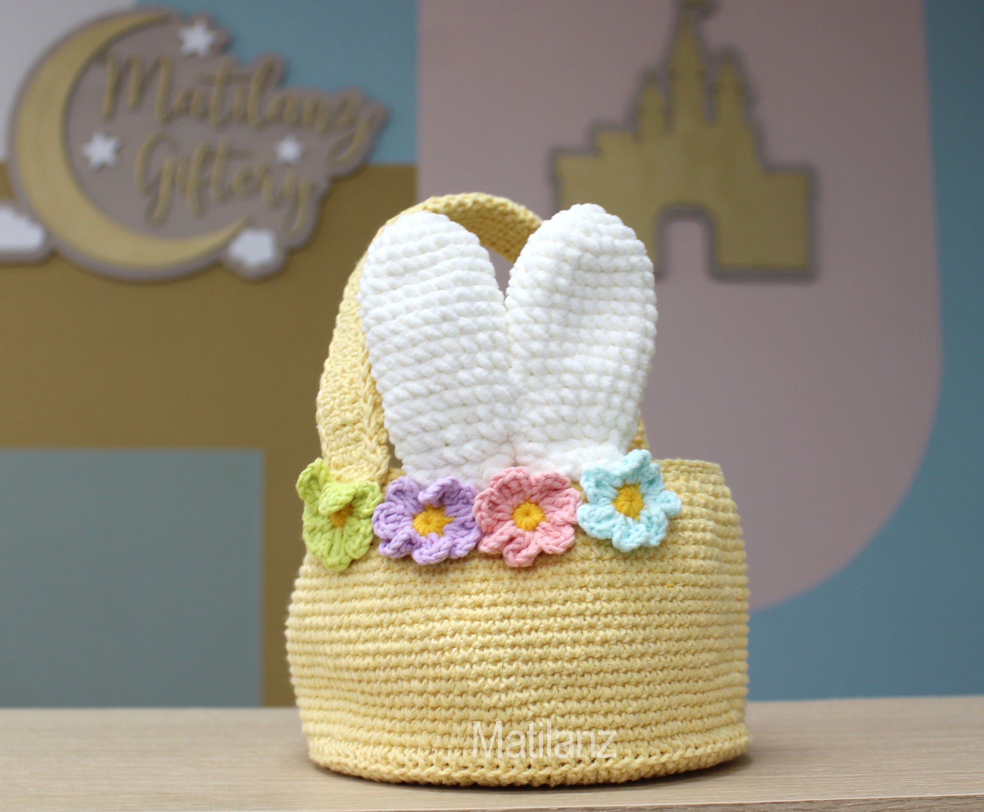 A handmade crochet Easter bunny basket with white ears and colorful flower trim.