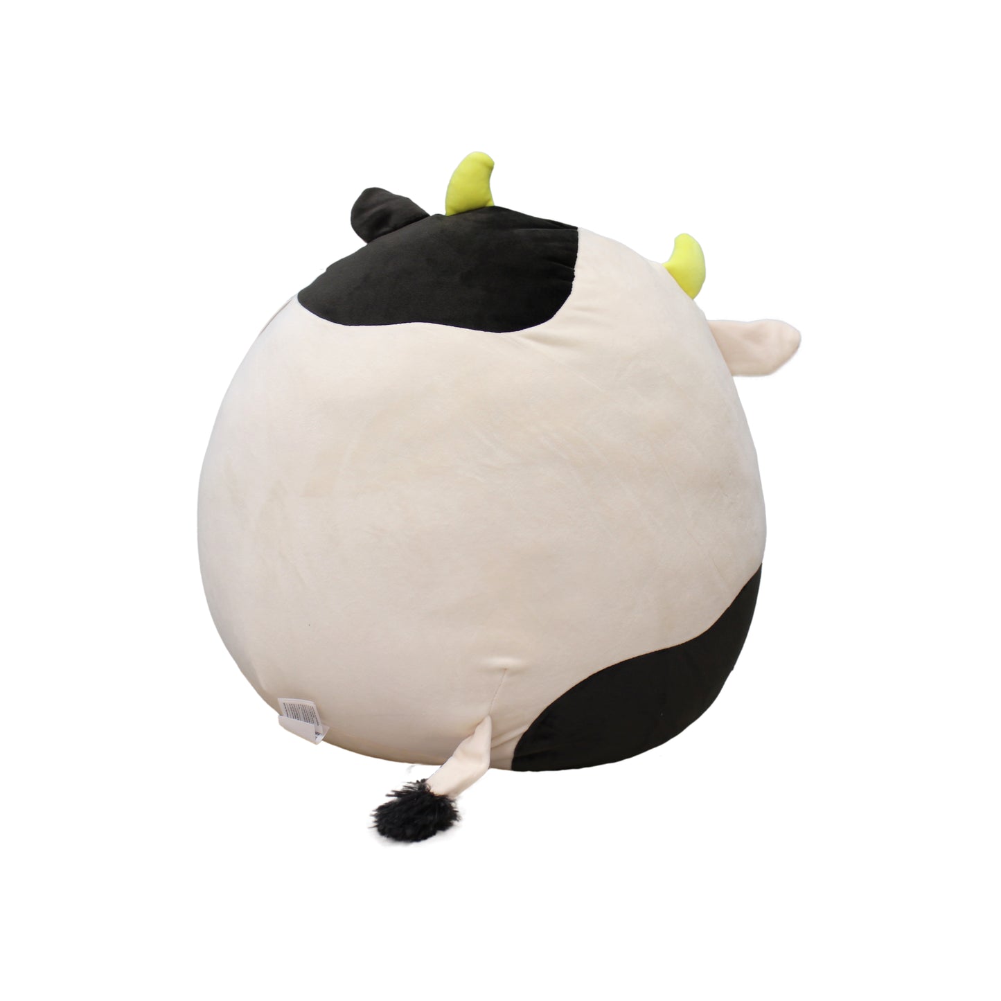 A large, round cow plush toy with black and white spots, yellow horns, and a fluffy tail.