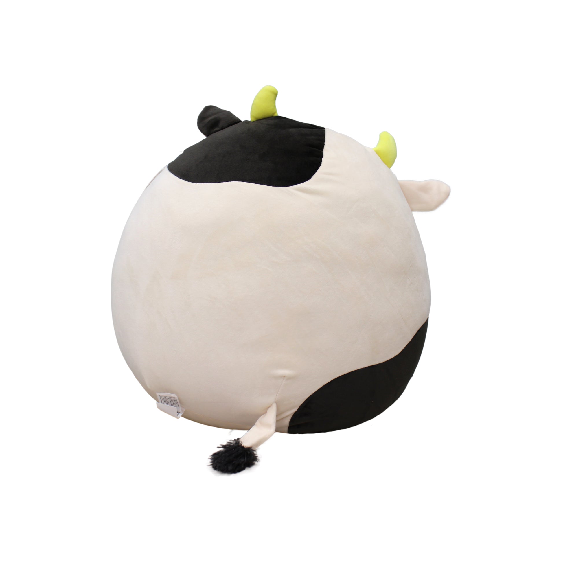 A large, round cow plush toy with black and white spots, yellow horns, and a fluffy tail.