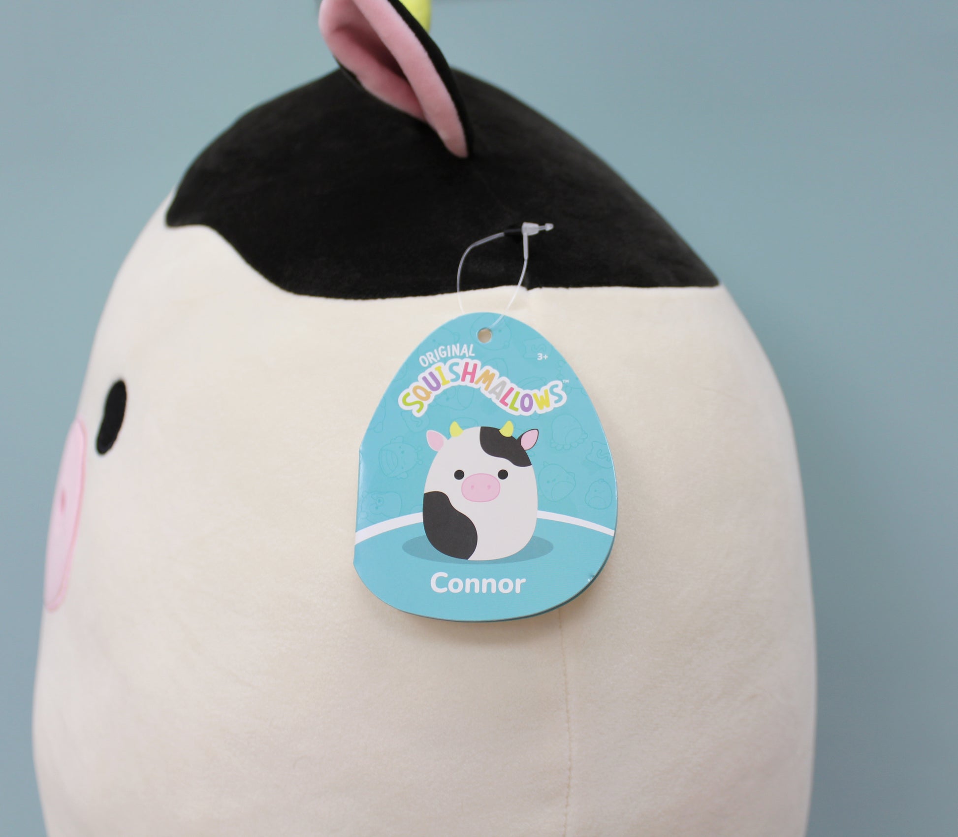 A large 16-inch plush cow with a soft white and black body, pink nose, and floppy ears.