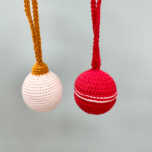 Crochet Christmas ball ornaments in white and red, featuring braided hanging loops for festive tree decor.