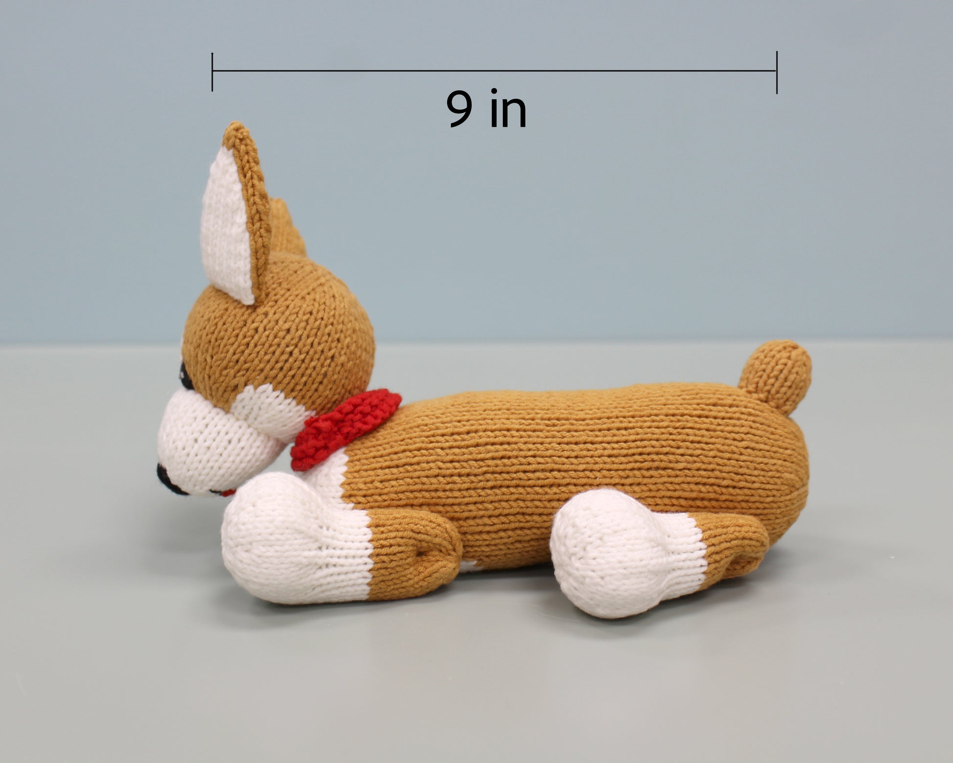 Handmade knitted corgi plush in brown and white, 9 inches long, with a red collar.