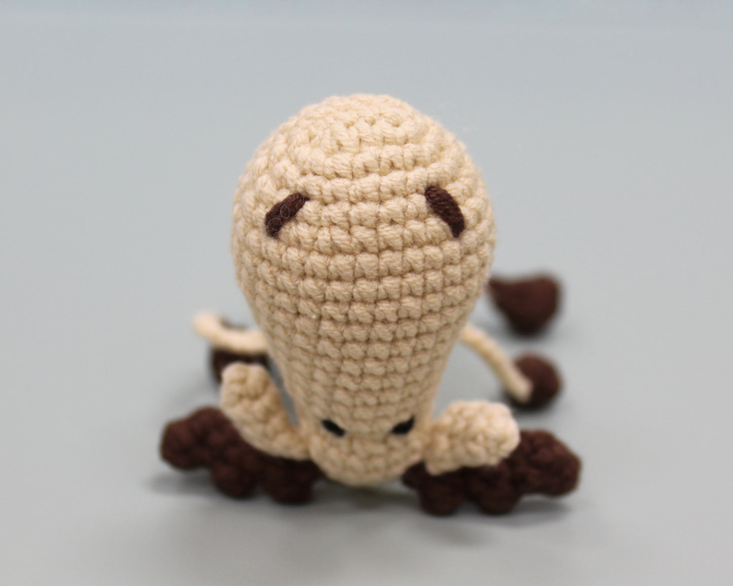 Handmade crochet keychain in beige and brown, featuring a plush moose design with a textured, cozy appearance.