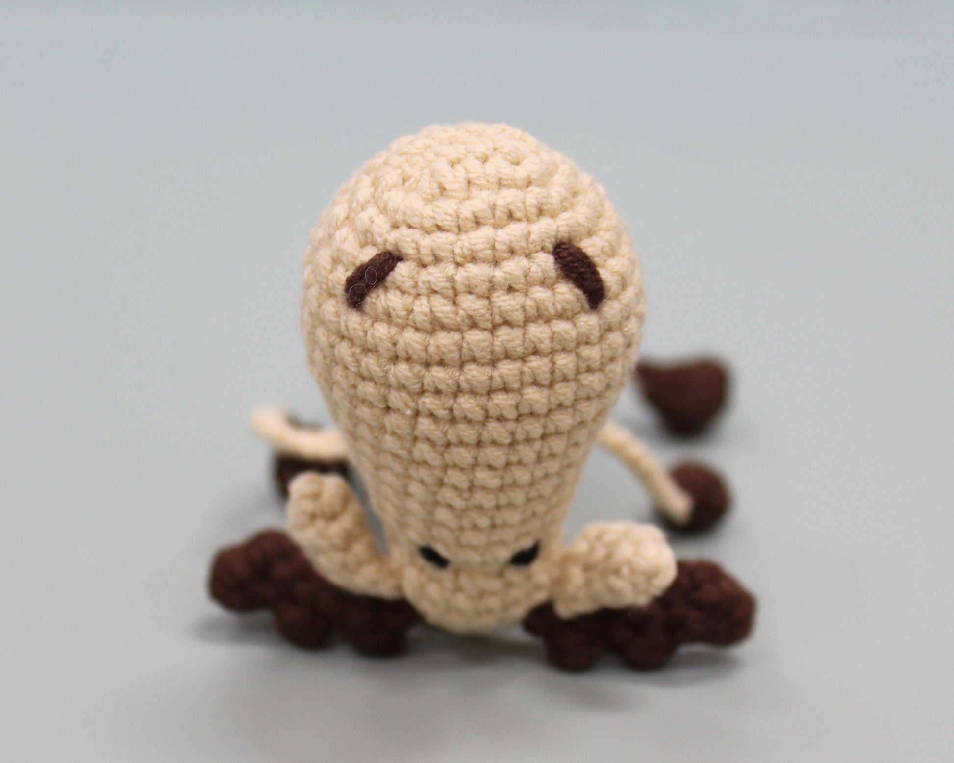 Handmade crochet keychain in beige and brown, featuring a plush moose design with a textured, cozy appearance.