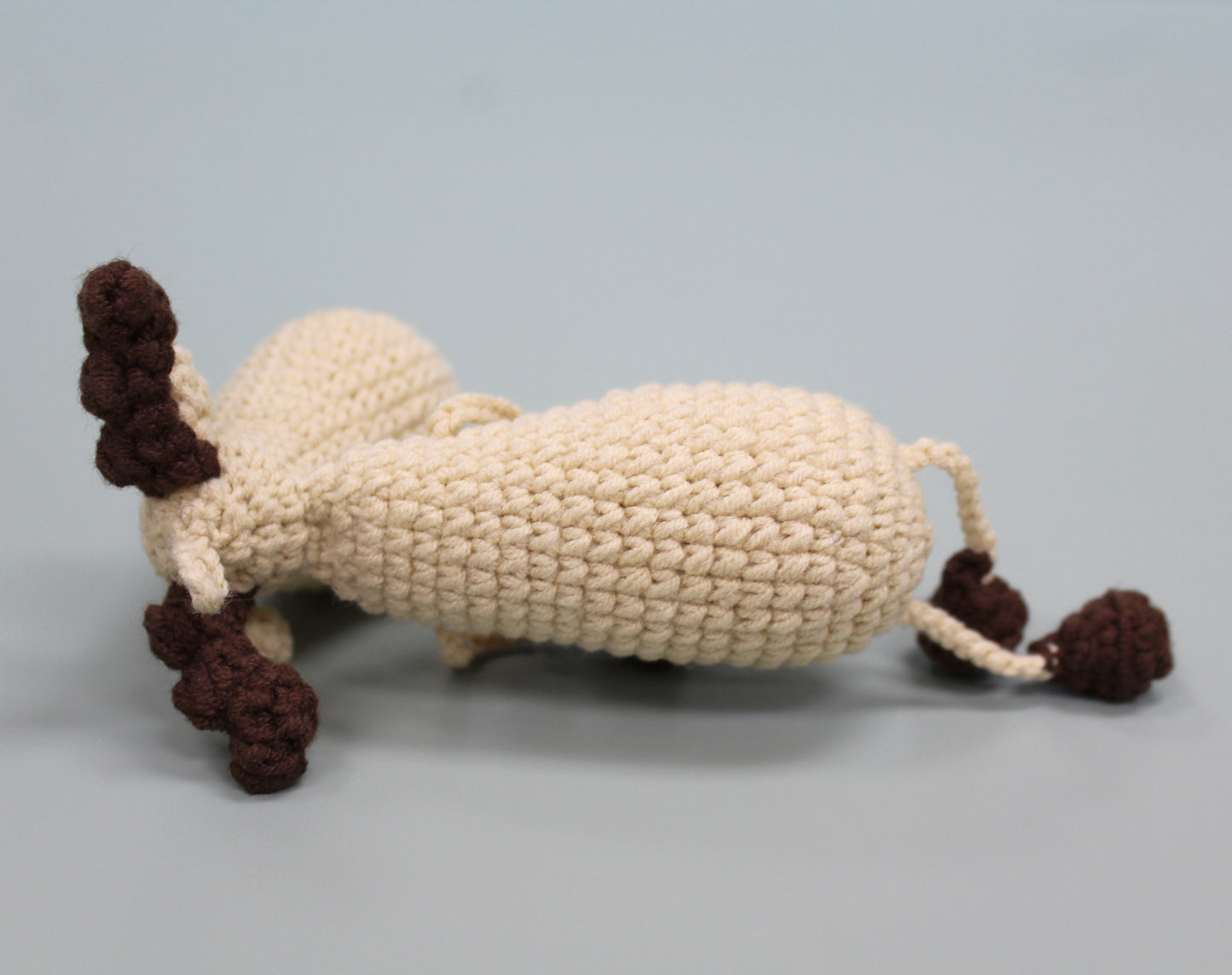 Handmade crochet keychain in cream with brown antlers and tail, crafted with plush material.