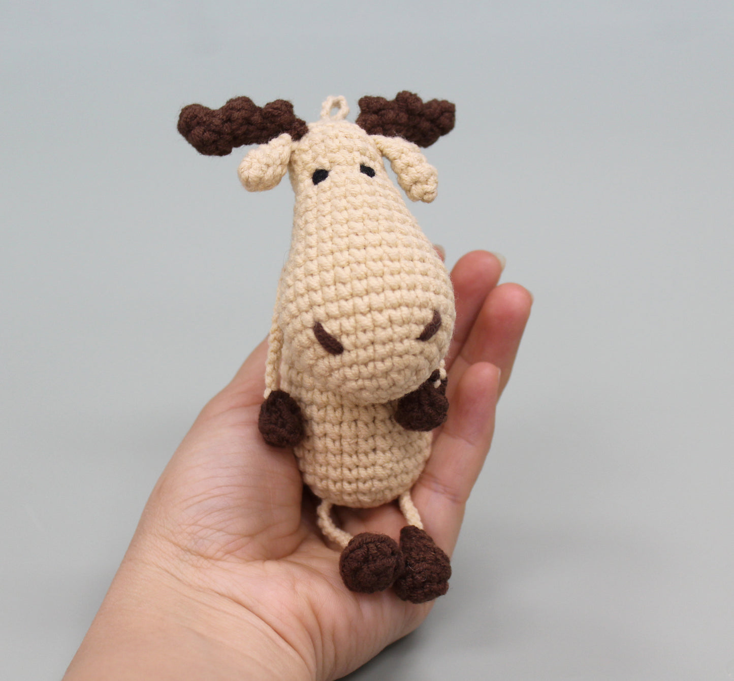 Handmade crochet moose keychain with brown antlers and legs, and a plush body.