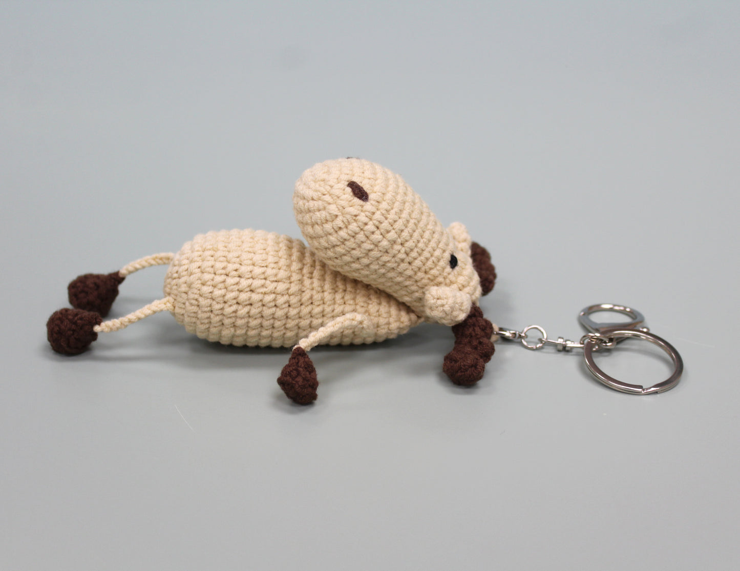 Handmade crochet keychain in cream and brown, featuring a plush moose design with a metal key ring.