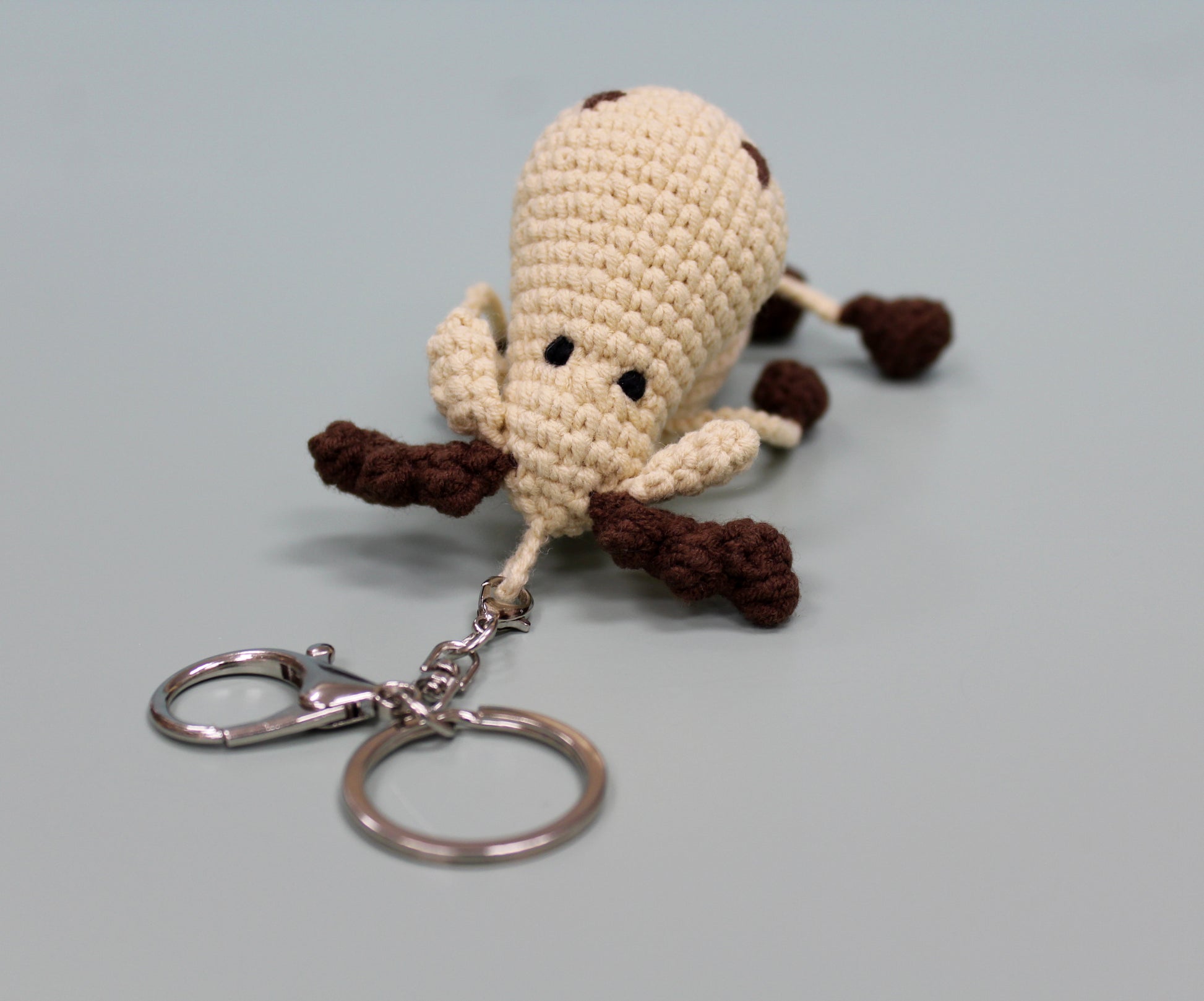 Handmade crochet keychain in beige and brown, featuring antlers and a plush texture.