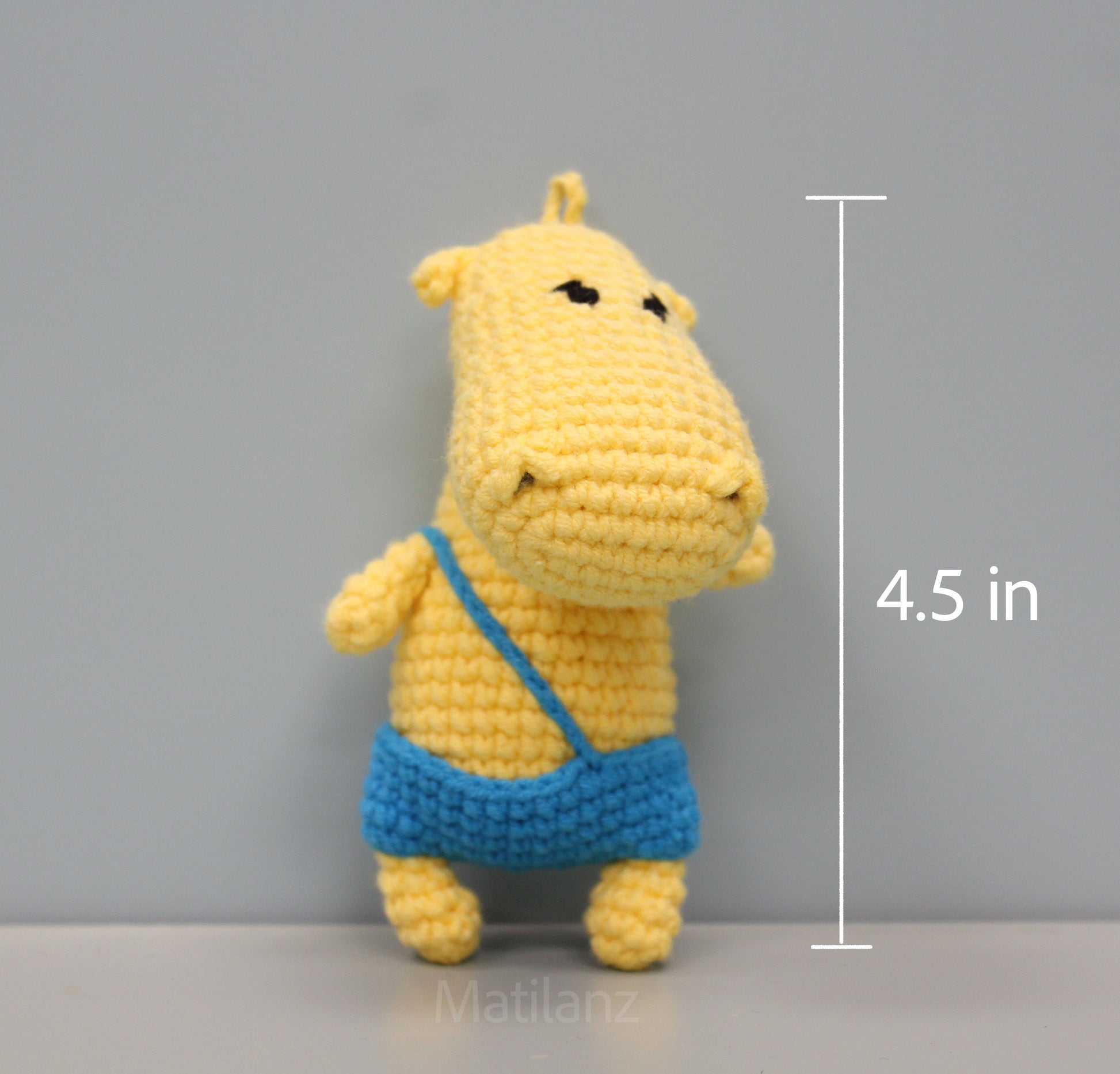 Handmade yellow crochet hippo keychain with blue overalls, approximately 4.5 inches tall.