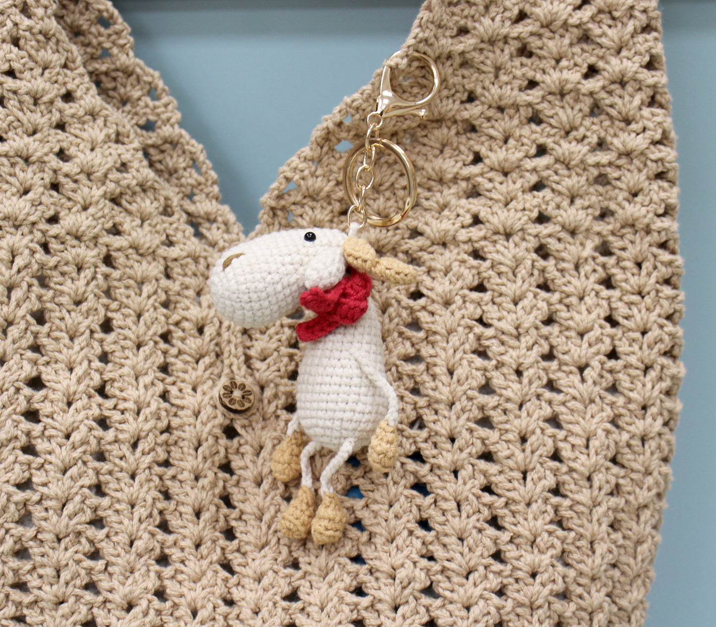 Handmade crochet moose keychain with a red scarf and gold hardware.