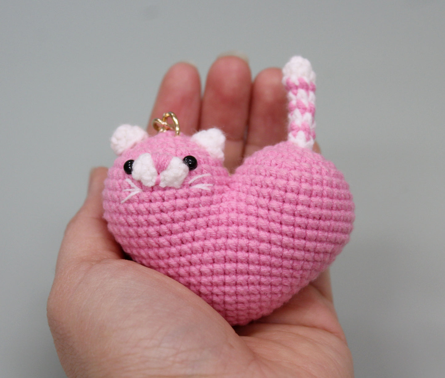 Pink and white crochet heart-shaped cat keychain with a gold ring.