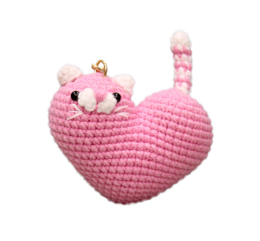 Pink and white crochet heart-shaped cat keychain with whiskers, eyes, and a tail.