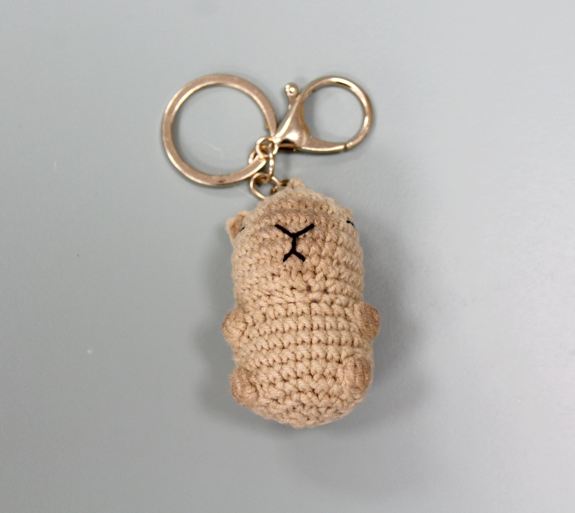 Handmade crochet capybara keychain in beige with a gold-colored metal ring and clasp.