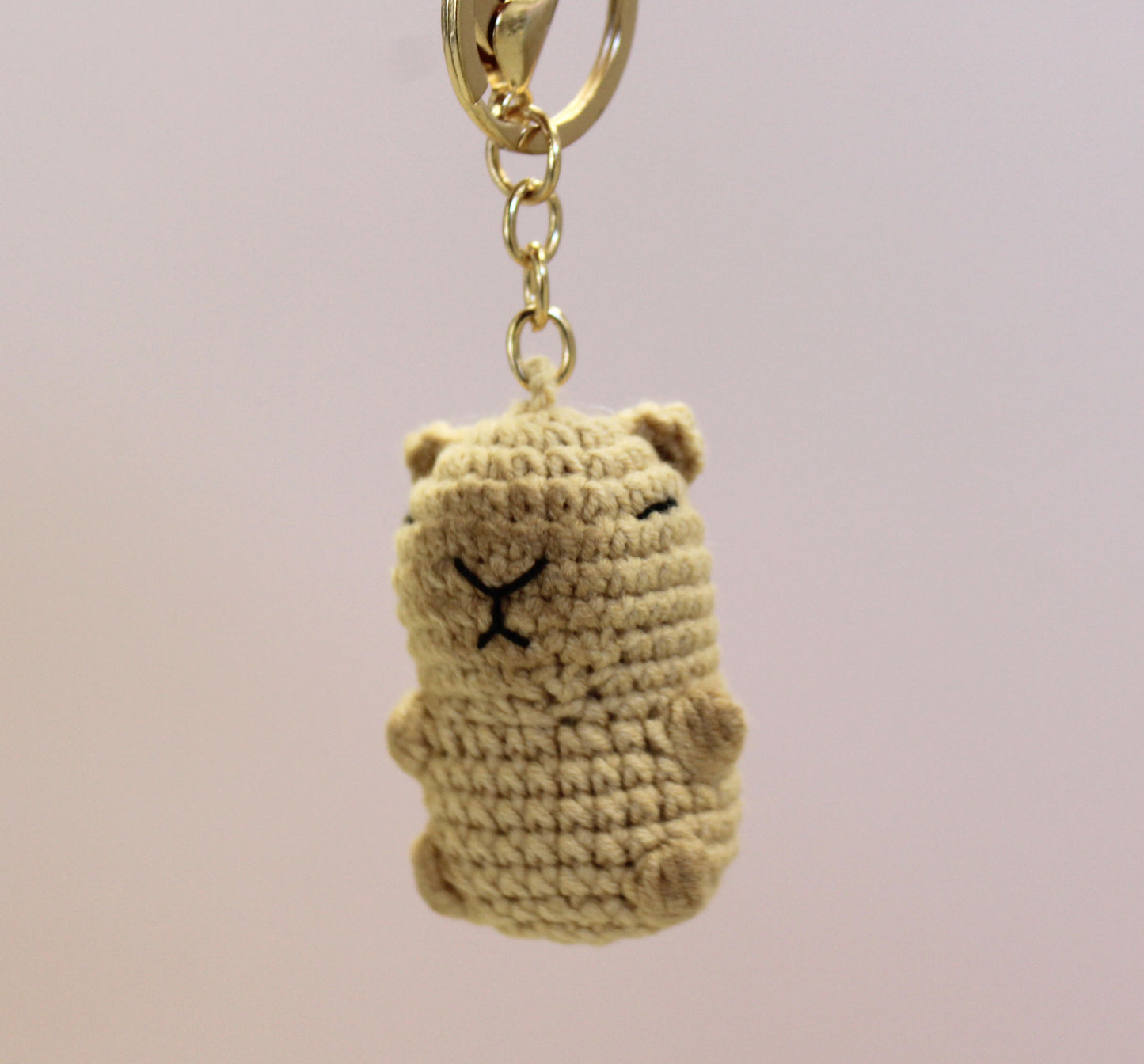 Handmade crochet capybara keychain in beige with a gold-colored metal ring and chain.