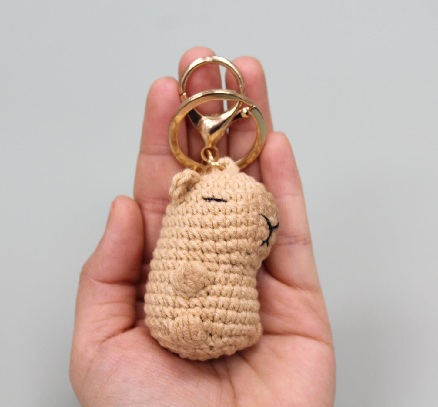 Handmade crochet capybara keychain in beige with a gold-colored metal ring and clasp.