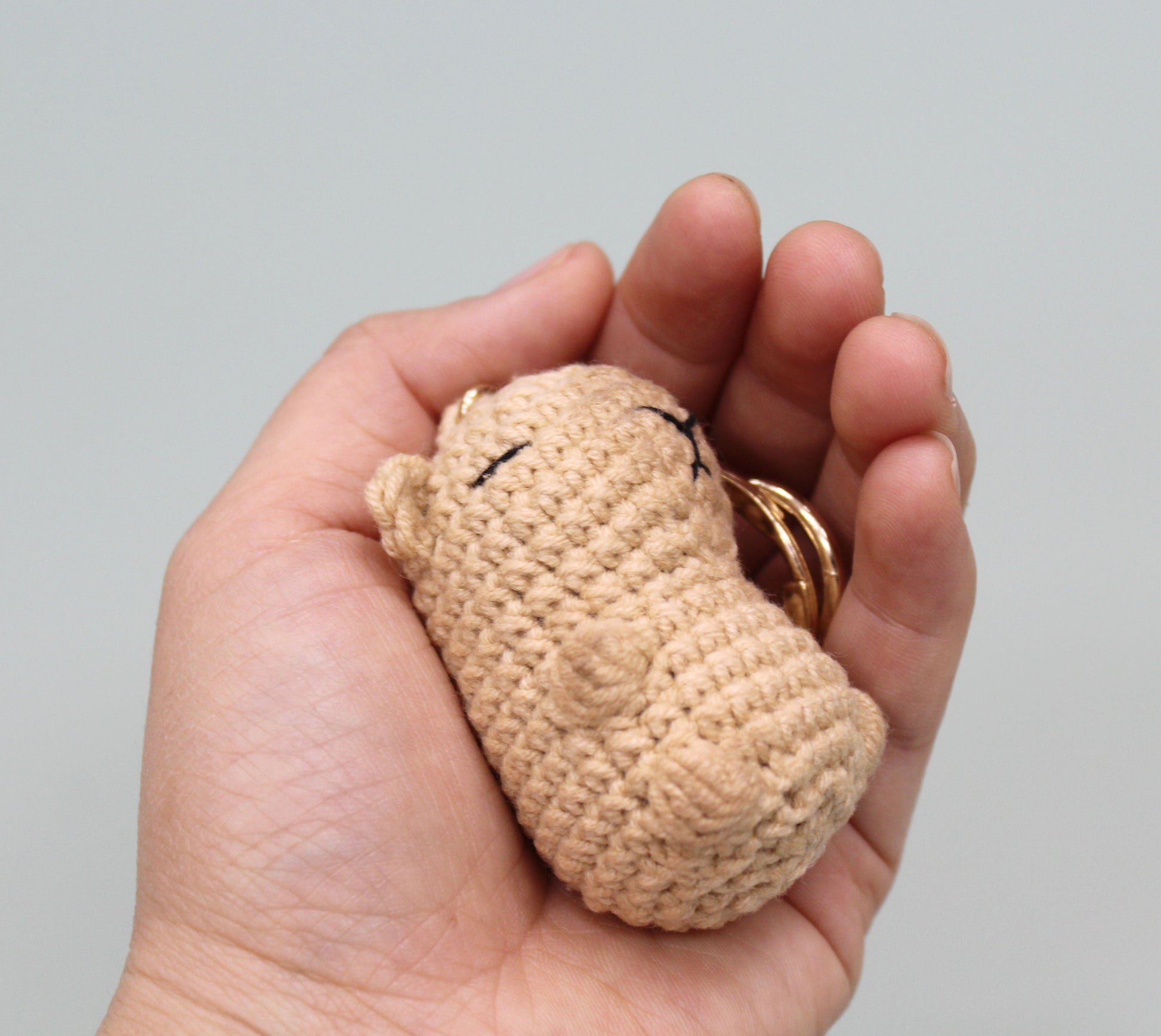 Handmade crochet capybara keychain in beige with embroidered eyes.