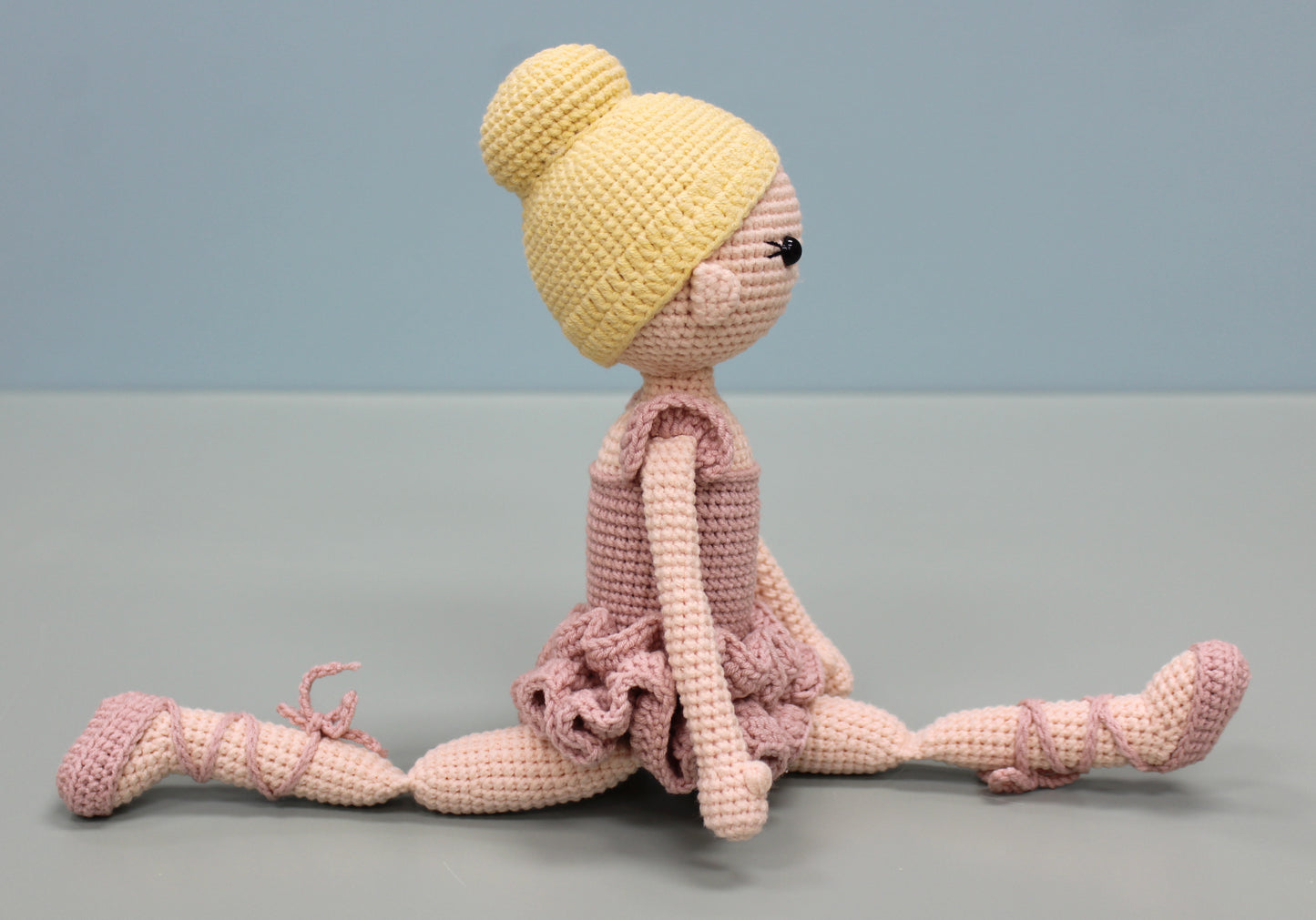 Handmade crochet ballerina doll in pink and yellow with a bun hairstyle and pointe shoes.
