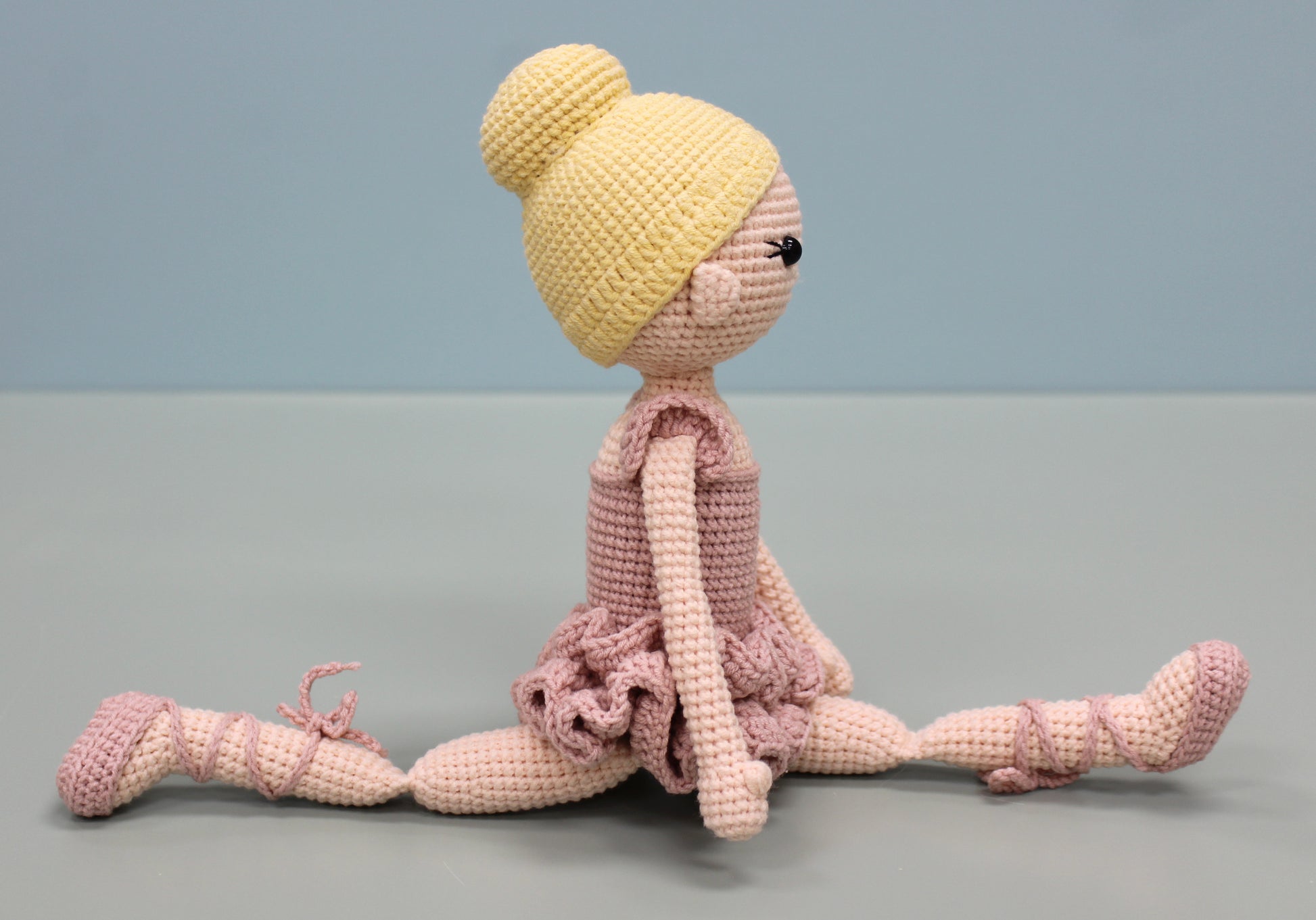 Handmade crochet ballerina doll in pink and yellow with a bun hairstyle and pointe shoes.