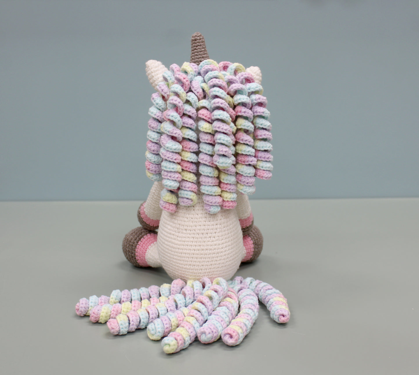 Handmade crochet unicorn plush with multicolored spiraled mane, tail, and pastel accents.