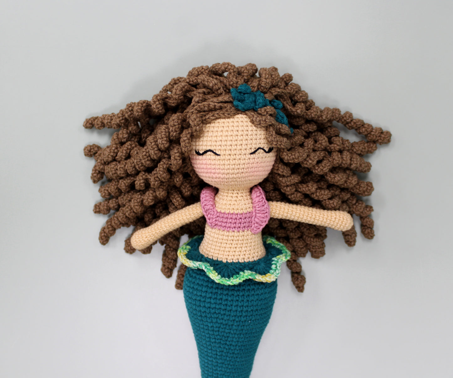 Handmade crochet mermaid doll with brown curly hair, a pink top, and a teal tail.