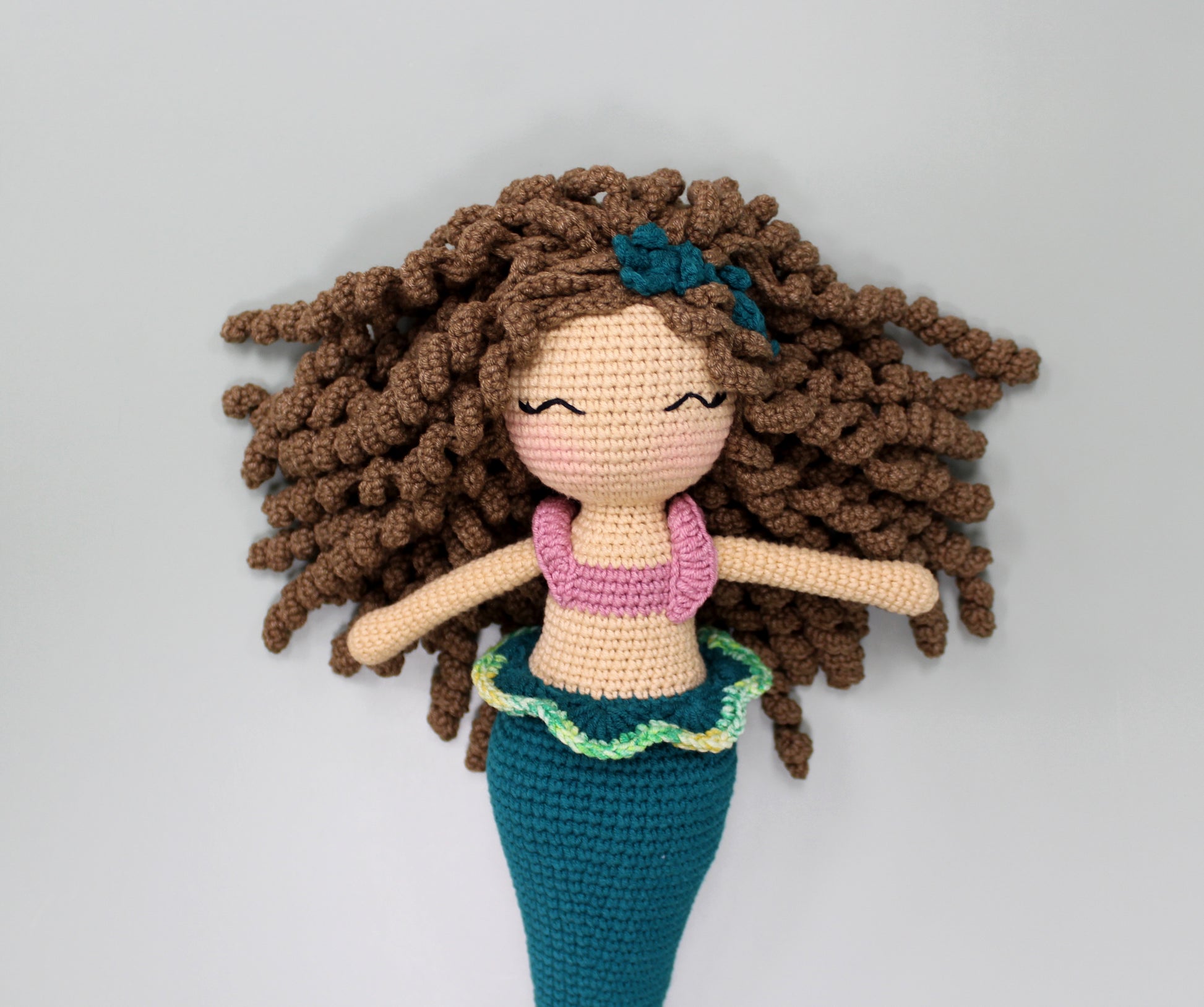 Handmade crochet mermaid doll with brown curly hair, a pink top, and a teal tail.