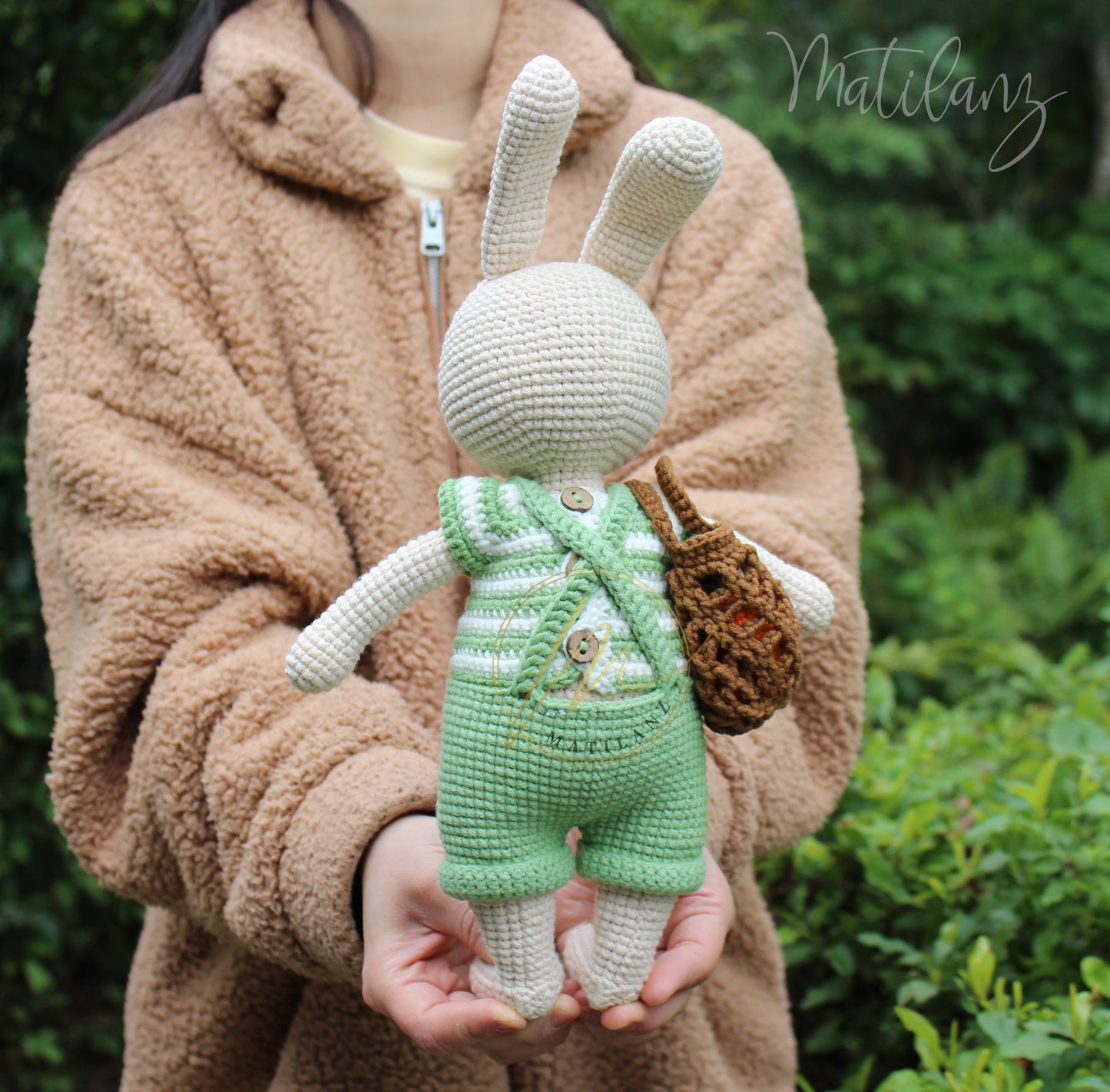 A handmade crochet Easter bunny dressed in green overalls with a matching basket.