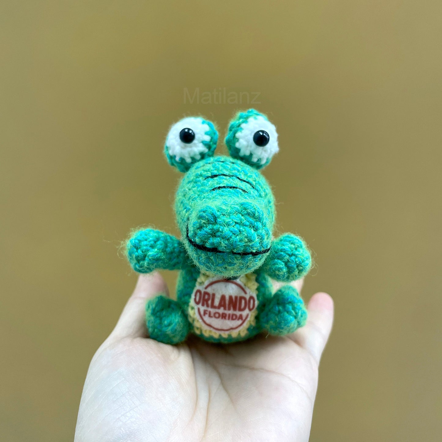 Crocheted teal gator keychain with white eyes and an "Orlando Florida" patch.
