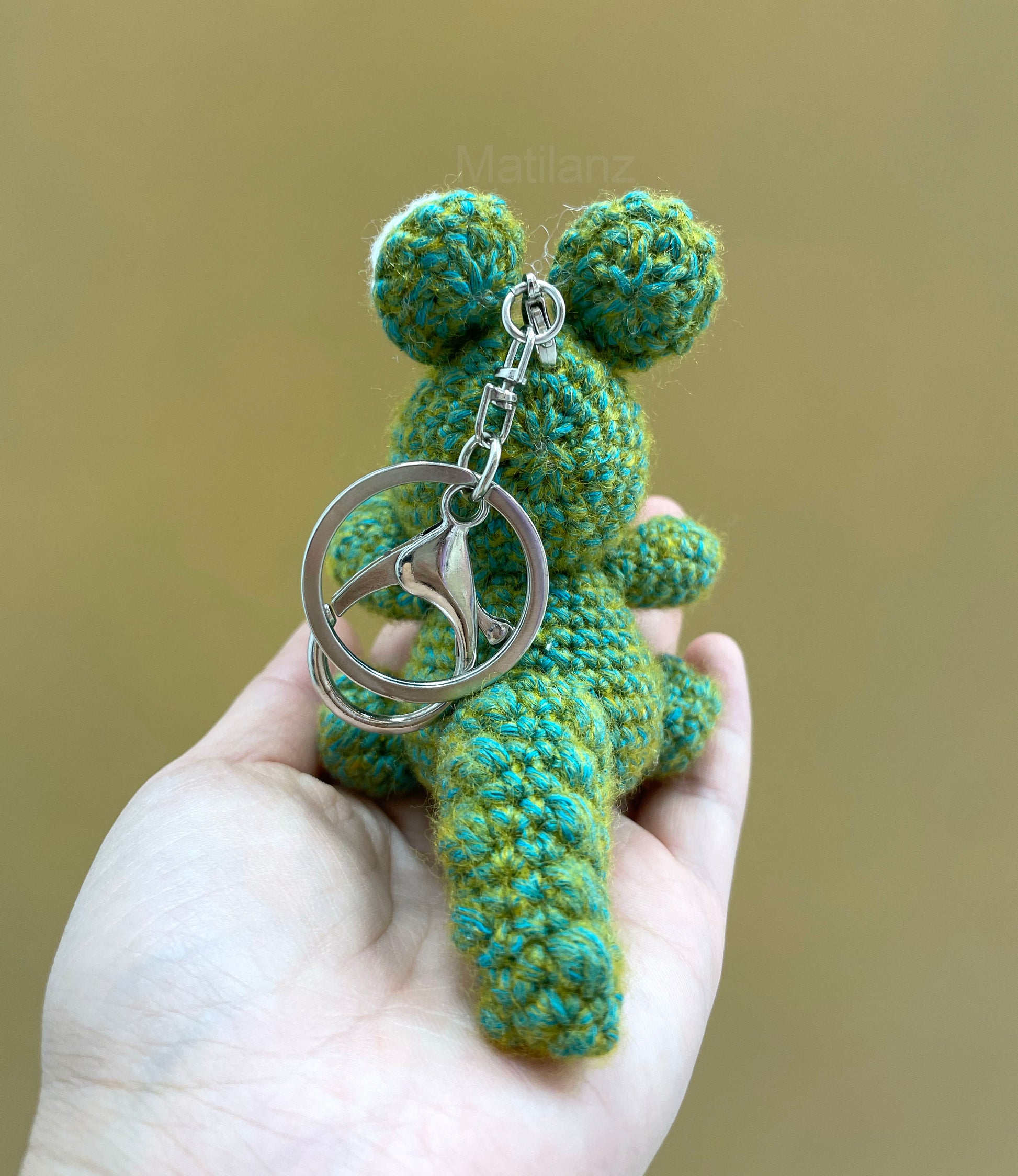 Cute green and teal crocheted gator-shaped keychain with silver ring.