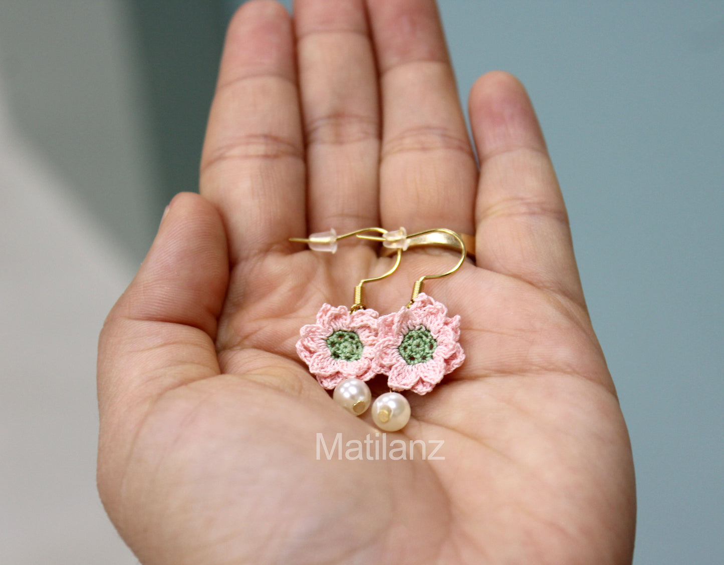 Crochet handmade earrings with pink flowers and green centers, featuring pearl accents.