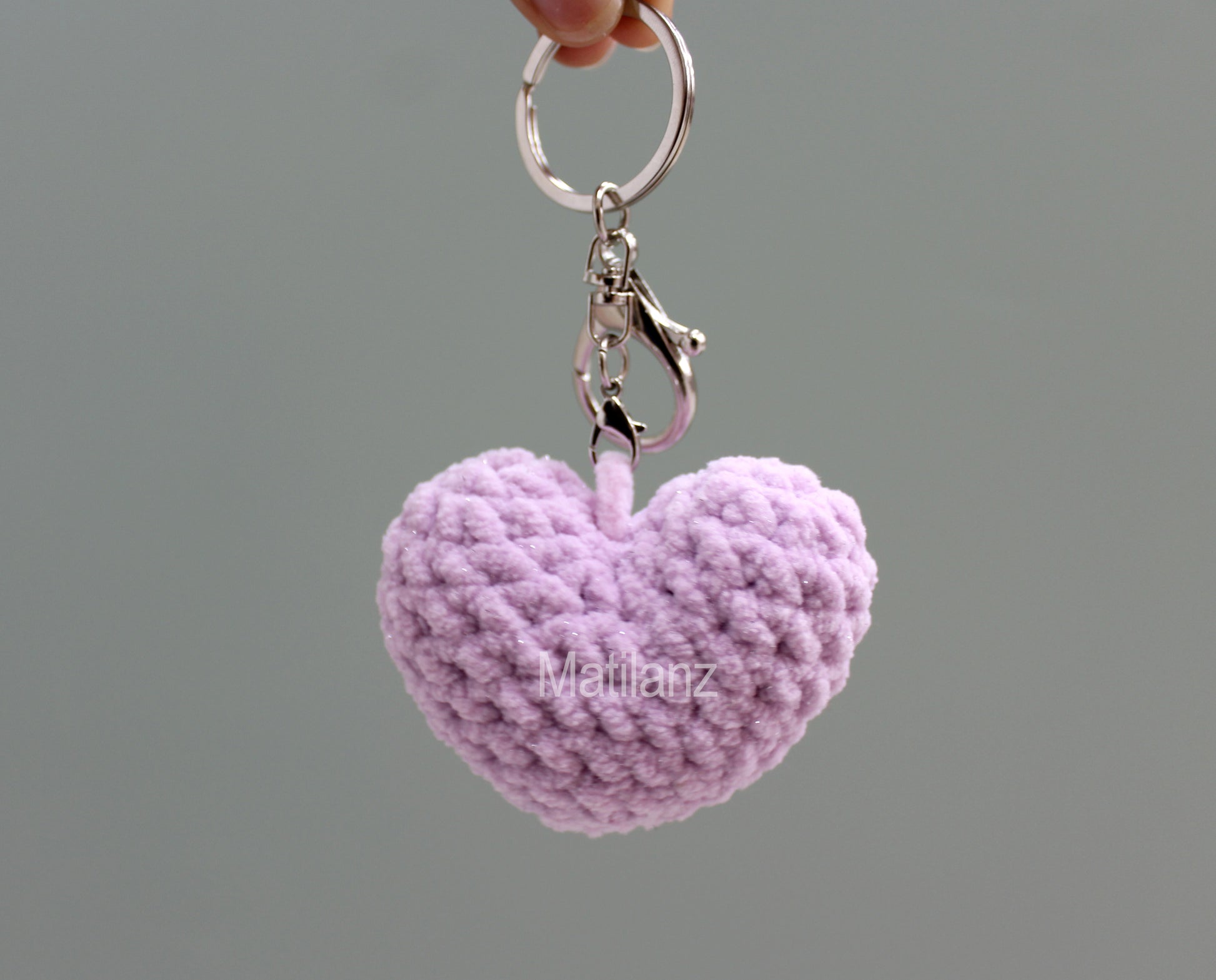 A handmade crochet heart keychain in light purple with a silver ring.