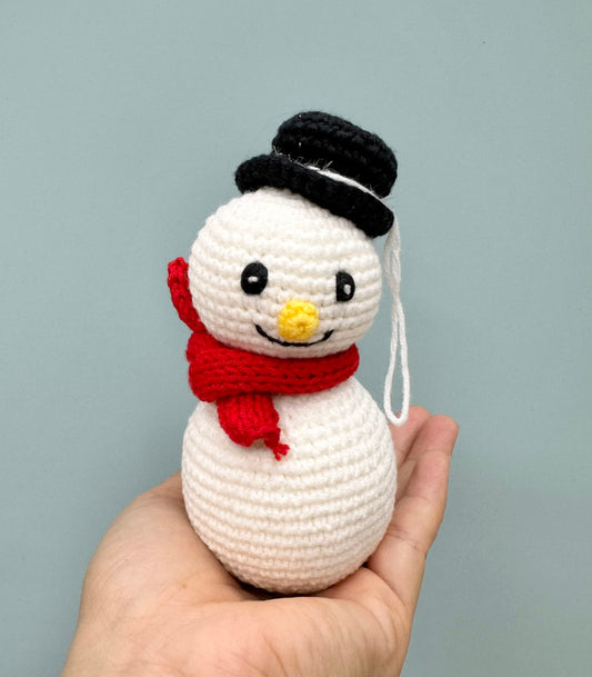 Crochet Christmas snowman with a black top hat, red scarf, and cheerful face.