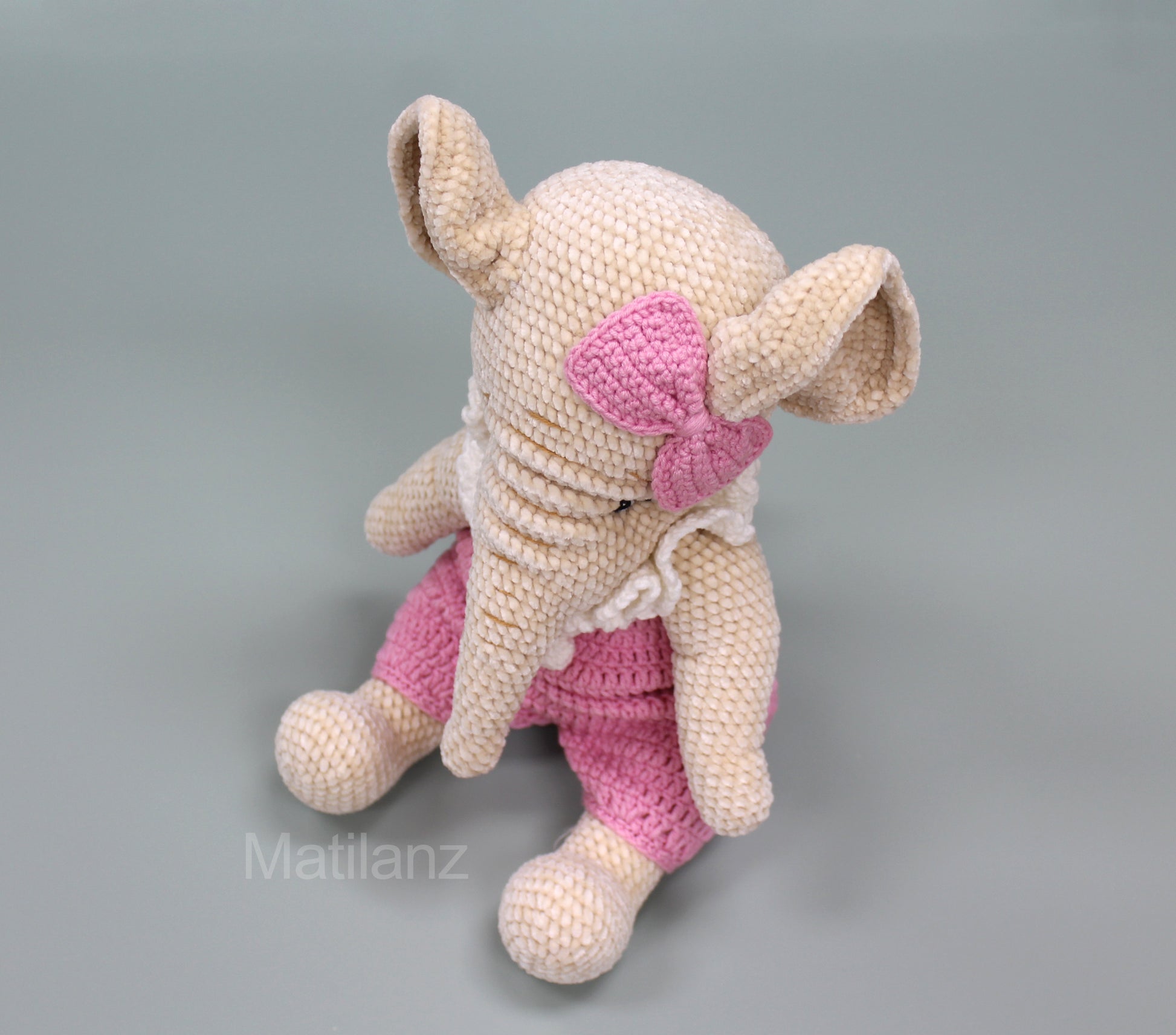 Crochet elephant in pink overalls and bow, 13 inches tall, handmade with soft yarn.