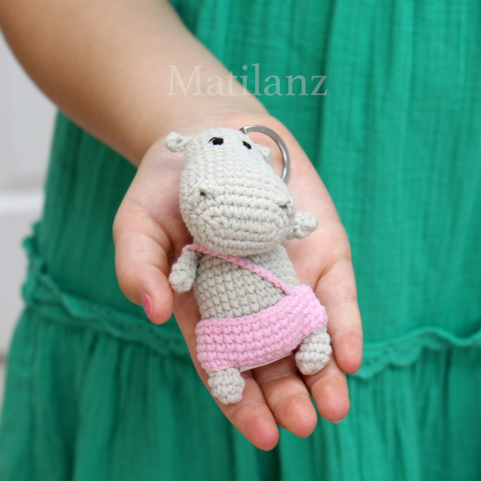 Handmade crochet hippo keychain in light gray with a pink crossbody strap and a metal key ring.