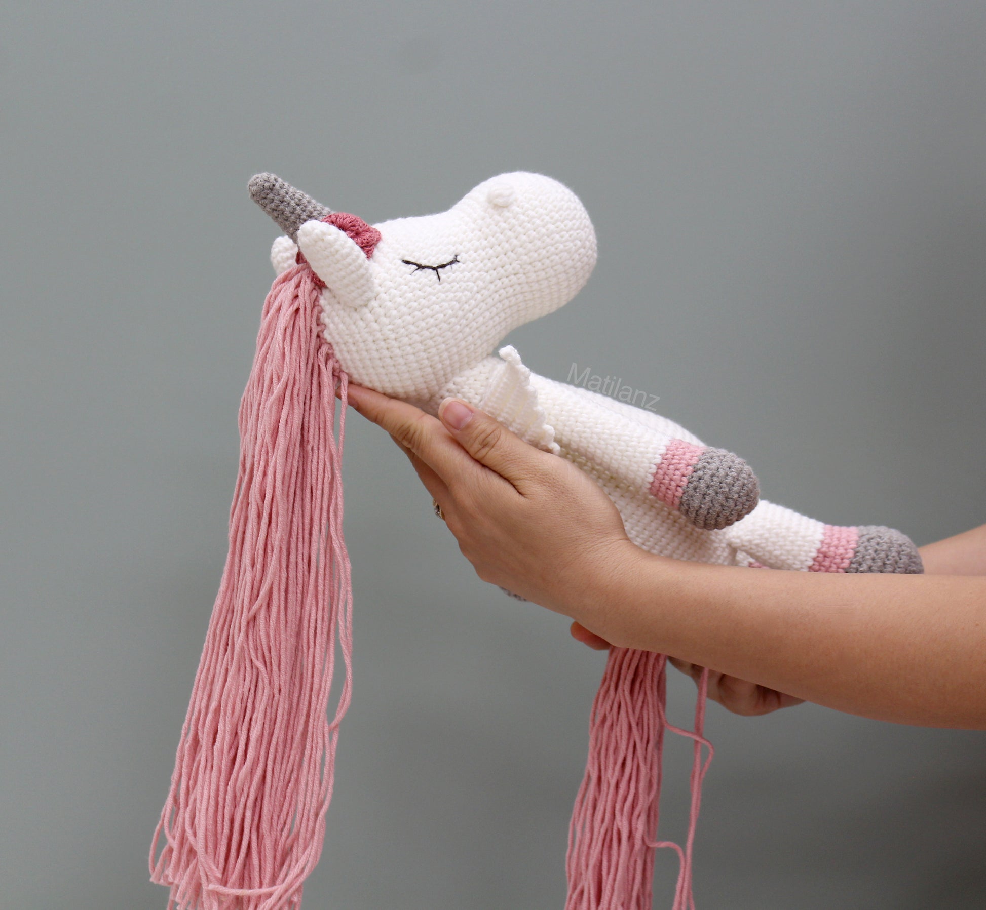 Handmade crochet unicorn horse with white body, pink mane, and gray wings, 14 inches long.