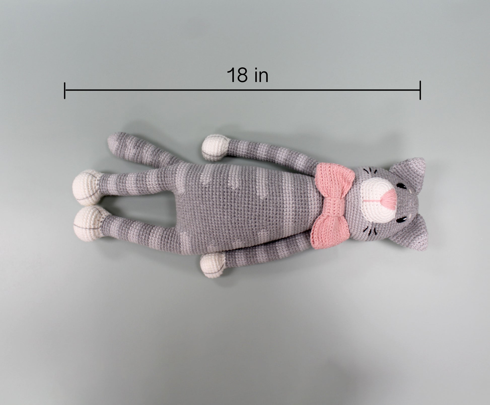 Gray crochet cat plush with pink bow, 18 inches long, featuring striped design and white accents.